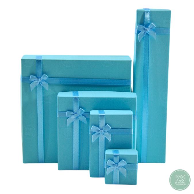 กล่องกระดาษขนาด 10x10x3.5 cm มีโบว์สีฟ้า ใส่เครื่องประดับ ภายในมีฟองน้ำบุผ้ากำมะหยี่ จัดวาง แหวน ต่าง สร้อย มอบเป็นของ