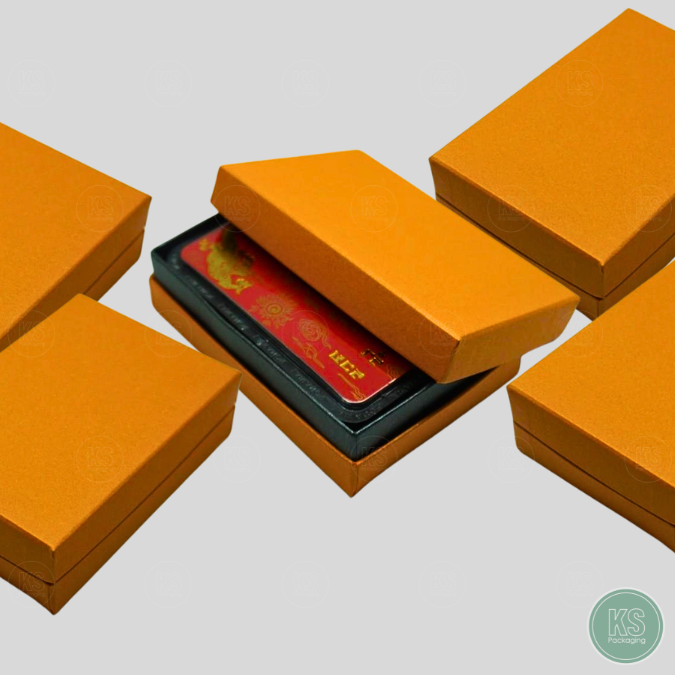 กล่องสีส้มมีฝาครอบ ใส่การ์ดทองคำแท่ง มีราคาไม่แพง แข็งแรงทนทาน ขนาด 7x10x3 cm มีรูปทรงสี่เหลี่ยม